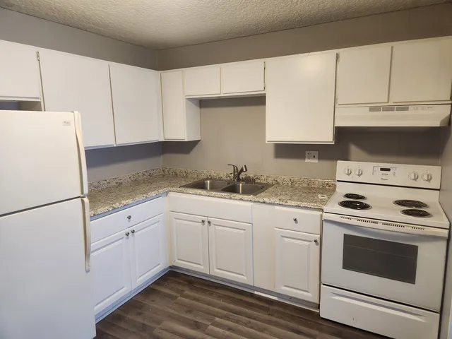 a kitchen with granite countertop white cabinets and white appliances