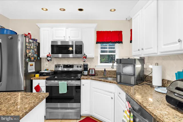 a kitchen with stainless steel appliances granite countertop a stove top oven a sink dishwasher and cabinets with wooden floor
