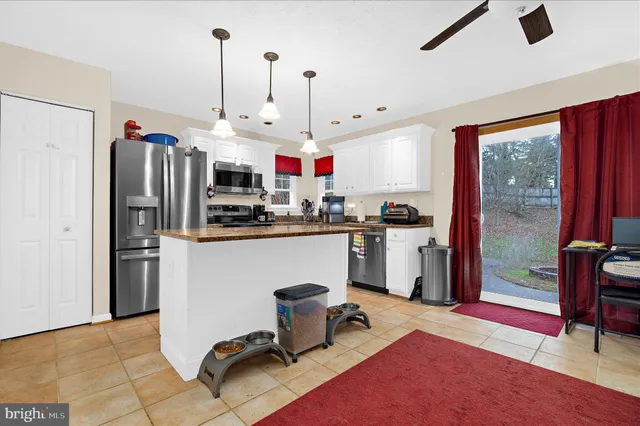 a kitchen with stainless steel appliances granite countertop a refrigerator a sink dishwasher a dining table and chairs with wooden floor