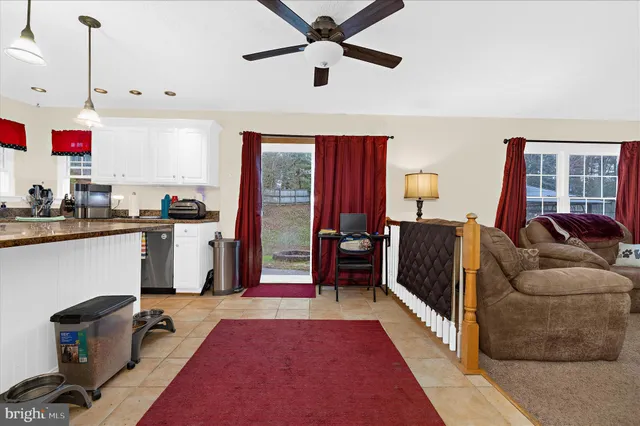 a living room with stainless steel appliances kitchen island granite countertop furniture a rug and a window
