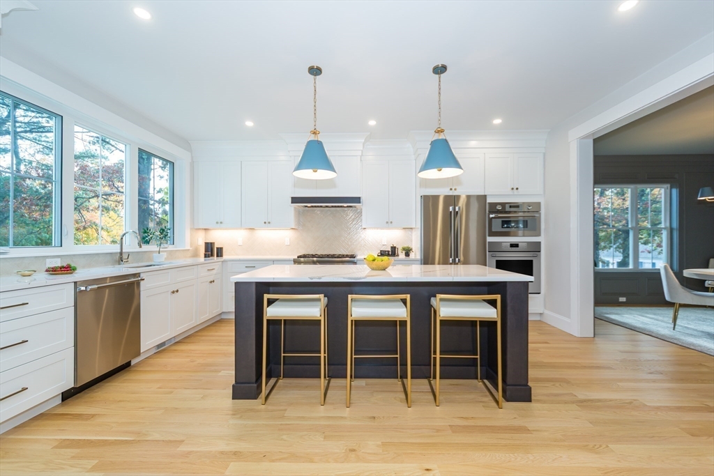 3 Ferndale Road Natick, MA 01760 - Photo 8 of 40 a kitchen with stainless steel appliances granite countertop a stove a sink dishwasher a dining table and chairs with wooden floor