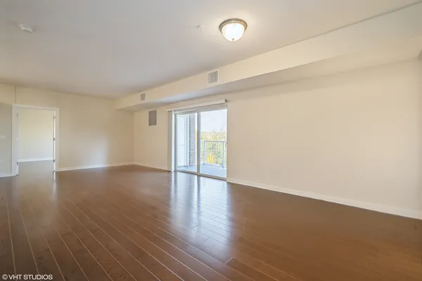 an empty room with wooden floor and natural light