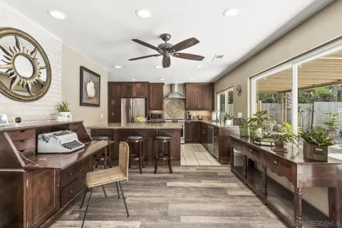 a kitchen with stainless steel appliances kitchen island granite countertop a stove a sink a dining table and chairs with wooden floor