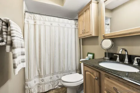 a bathroom with a granite countertop sink a toilet and a mirror