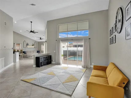 a living room with furniture a ceiling fan and kitchen view