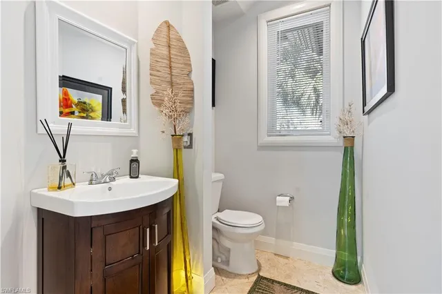 a bathroom with a sink a mirror a toilet and a window