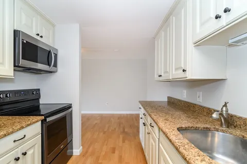 a kitchen with granite countertop a sink a stove and microwave