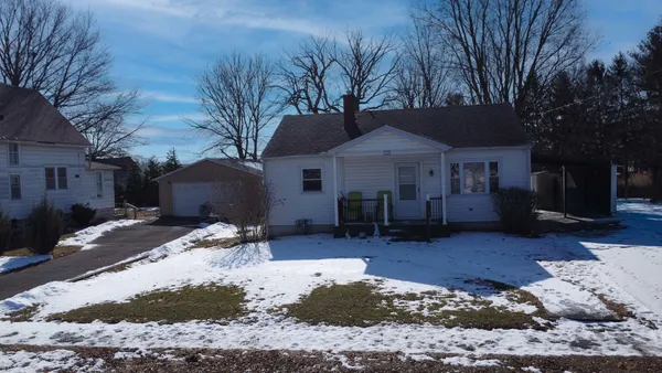 a front view of a house with a yard covered in snow
