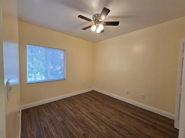 a view of a room with wooden floor and a ceiling fan