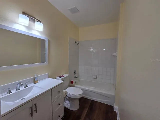 a bathroom with a granite countertop sink toilet a large mirror a bathtub and shower