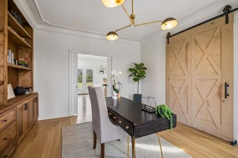 a dining room with wooden floor a chandelier a wooden table and chairs