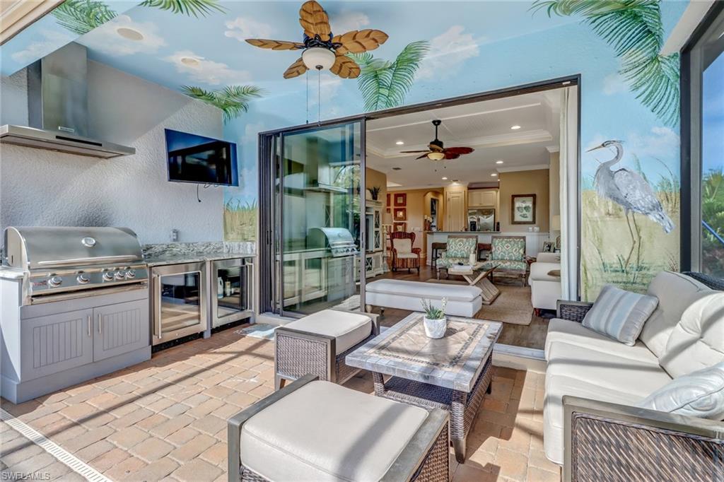3280 Miyagi Lane Naples, FL 34114 - Photo 22 of 25 a living room with stainless steel appliances kitchen island granite countertop furniture a flat screen tv and a chandelier