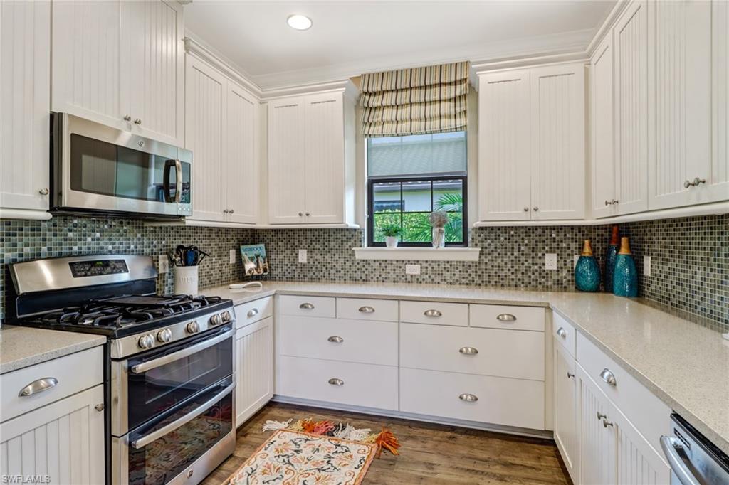 3280 Miyagi Lane Naples, FL 34114 - Photo 5 of 25 a kitchen with granite countertop white cabinets stainless steel appliances and a window