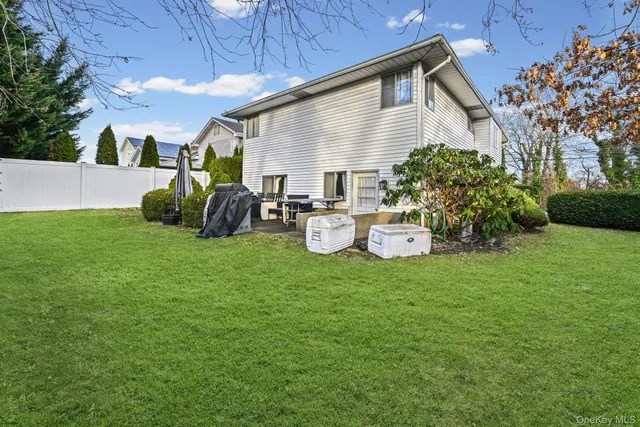 a backyard of a house with table and chairs plants and large tree