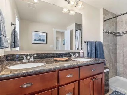 a bathroom with a granite countertop sink a toilet a mirror and shower