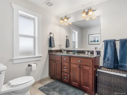 a bathroom with a granite countertop sink a mirror and a toilet