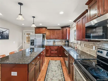 a kitchen with stainless steel appliances granite countertop a stove sink microwave and refrigerator