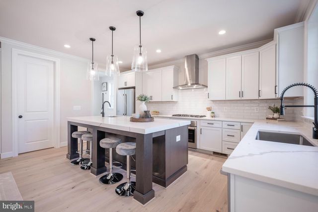a kitchen that has a lot of cabinets in it with stainless steel appliances granite countertop a sink a stove and a wooden floors