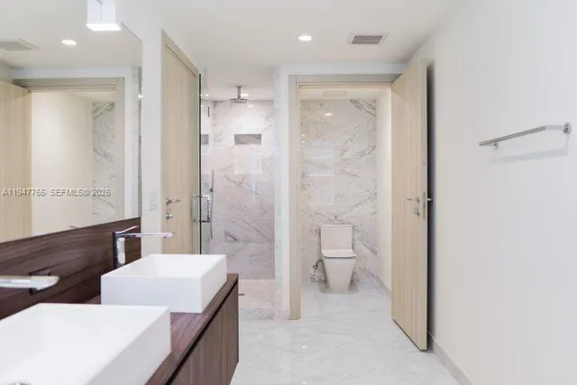 a bathroom with a double vanity sink toilet mirror and bathtub