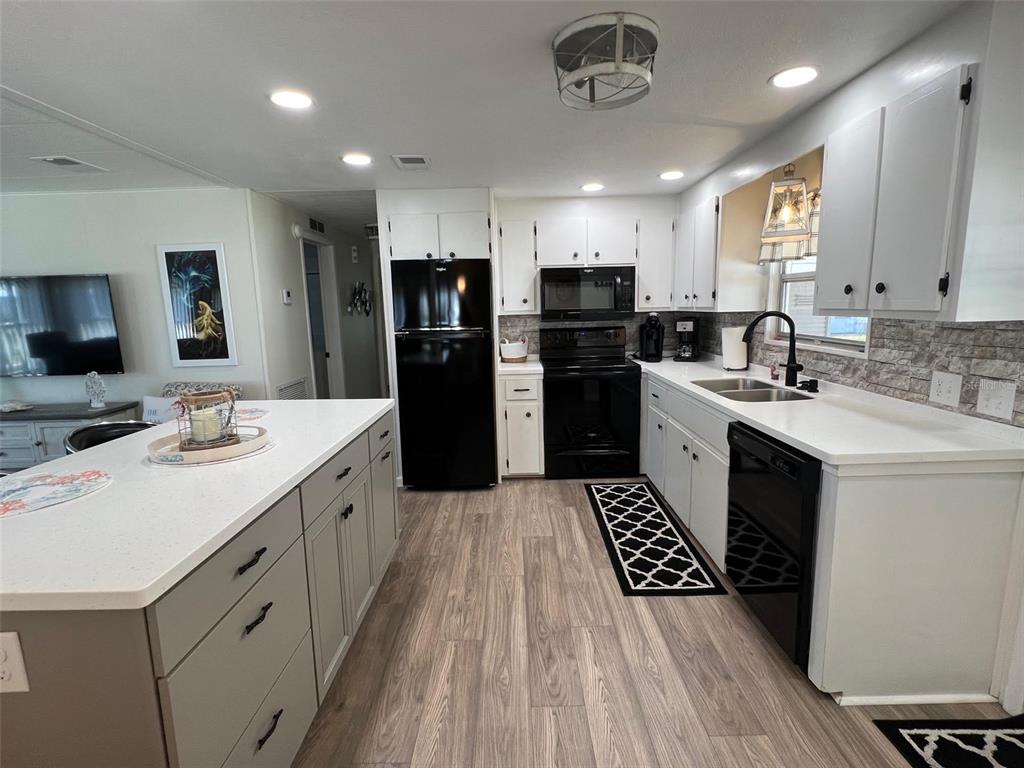 825 Coconut Palm Largo, FL 33778 - Photo 15 of 30 a kitchen with stainless steel appliances kitchen island a sink dishwasher a refrigerator and a stove with wooden floor
