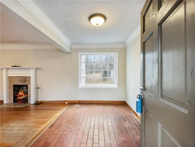 an empty room with wooden floor fireplace and windows