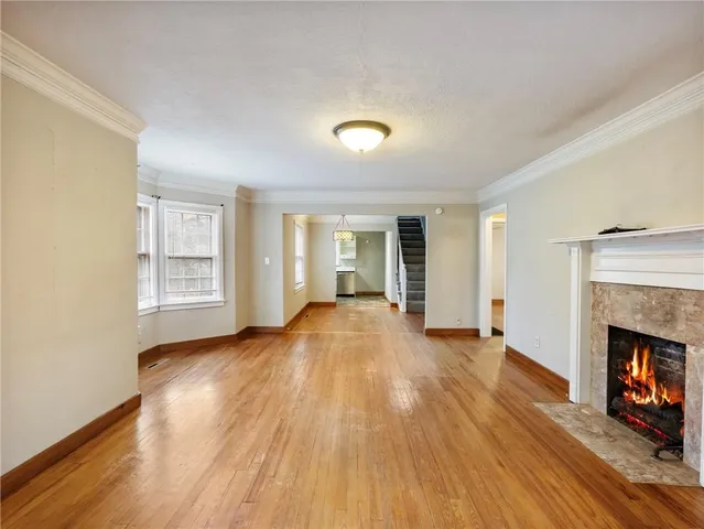a view of an empty room with wooden floor fireplace and a window