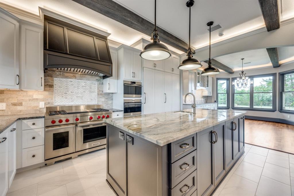 3244 Joe Davis Road Whitewright, TX 75491 - Photo 4 of 28 Kitchen with stainless steel appliances, decorative backsplash, an island with sink, light stone counters, and a chandelier