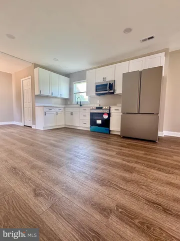 a view of kitchen with stainless steel appliances granite countertop a stove top oven a refrigerator a sink and dishwasher with wooden floor