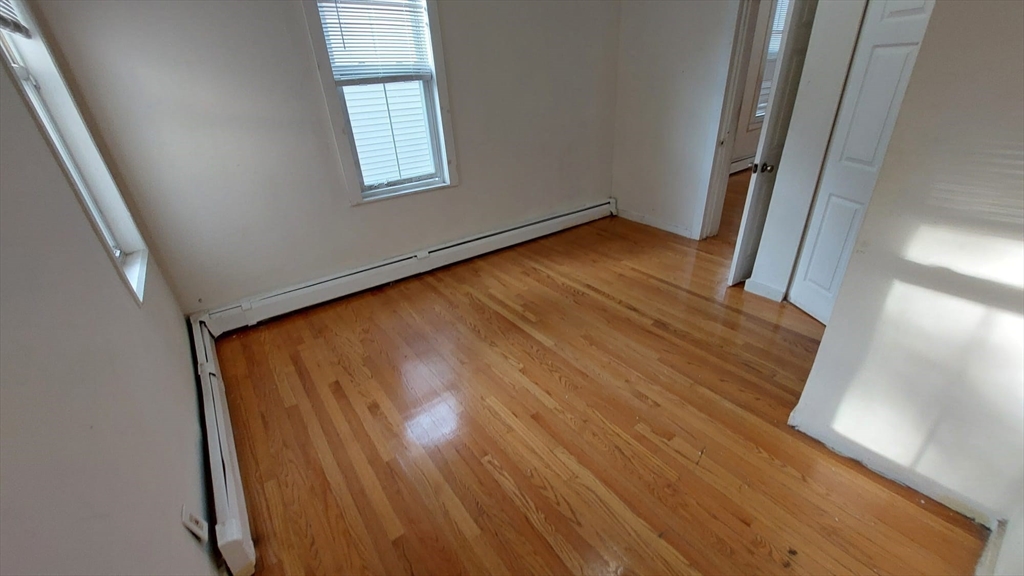 124 Marcella Street, Unit 1 Boston, MA 02119 - Photo 8 of 13 an empty room with wooden floor and windows