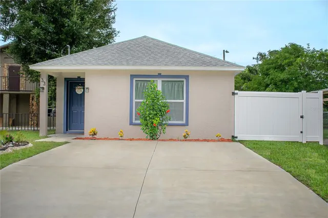 a view of a house with potted plants and a large tree