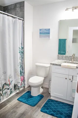 a bathroom with a granite countertop sink toilet a mirror and shower