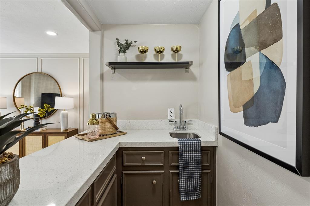 4962 Thunder Road Dallas, TX 75244 - Photo 12 of 26 Wet bar featuring quartz countertops, a stainless steel sink with a chrome faucet, and dark cabinetry