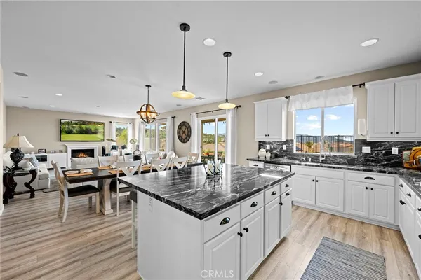 a kitchen with granite countertop a stove a sink a dining table and chairs with wooden floor