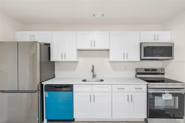 a kitchen with stainless steel appliances granite countertop a refrigerator stove top oven a sink and dishwasher