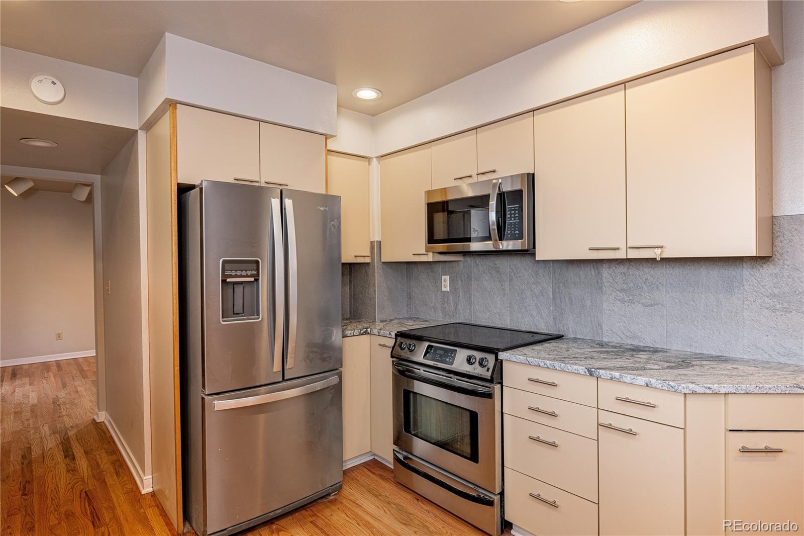 541 Monroe Street, Unit B Denver, CO 80206 - Photo 15 of 37 a kitchen with stainless steel appliances granite countertop a refrigerator stove and microwave