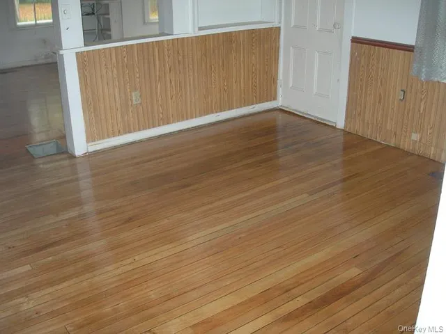 an empty room with wooden floor closet and windows