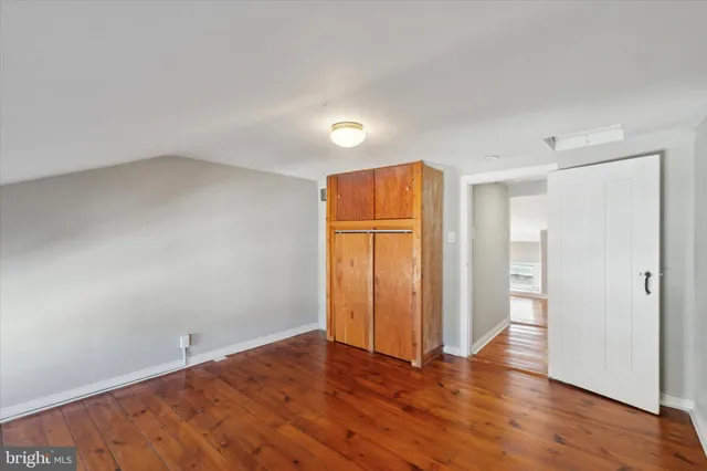 an empty room with wooden floor and closet area