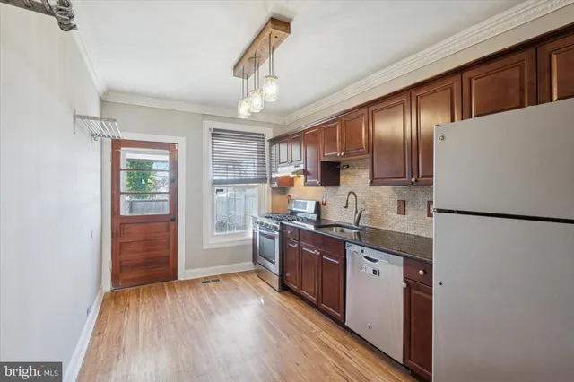 a kitchen with stainless steel appliances granite countertop a refrigerator a stove a sink dishwasher and a refrigerator with wooden floor