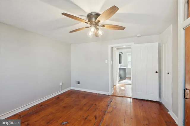 an empty room with wooden floor fan and windows