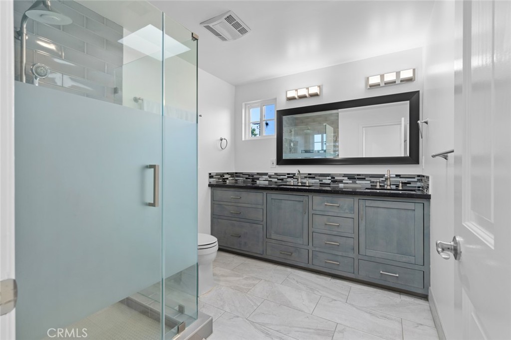 17131 Autumn Huntington Beach, CA 92647 - Photo 31 of 36 a bathroom with a granite countertop sink a mirror and a shower