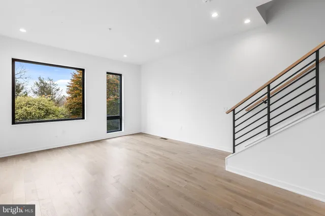 a view of an empty room with wooden floor and a painting on the wall