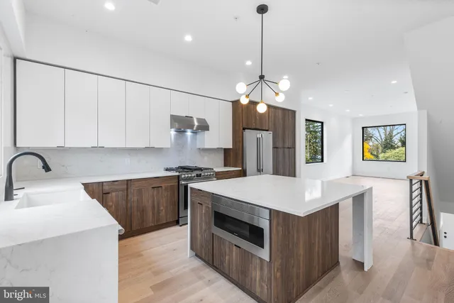 a kitchen with stainless steel appliances a sink a stove a refrigerator cabinets and wooden floor