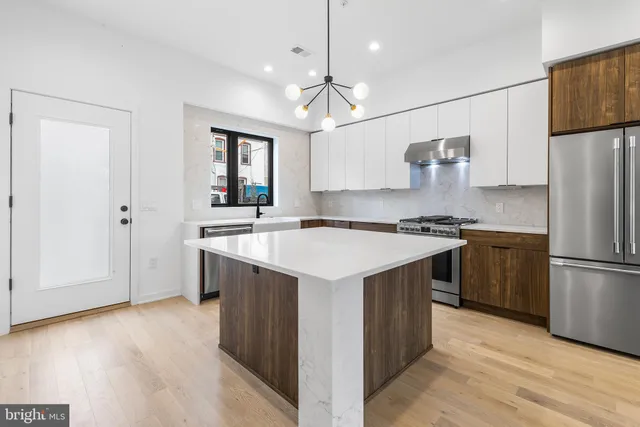 a kitchen with a sink a refrigerator a stove and white cabinets with wooden floor