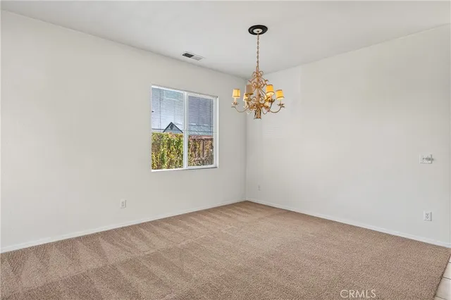 an empty room with a chandelier fan and windows