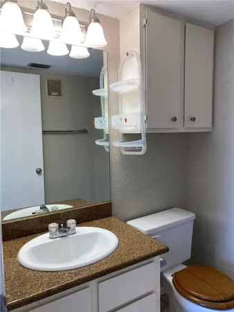 a bathroom with a granite countertop sink and a toilet