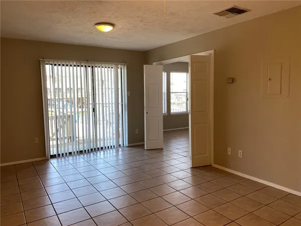 a view of an empty room and chandelier fan