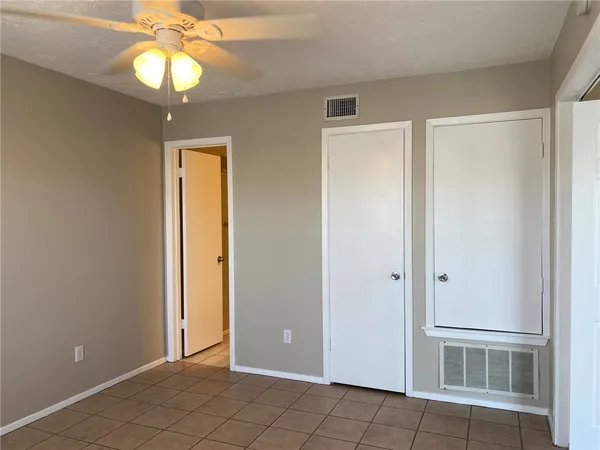 an empty room with windows and chandelier fan