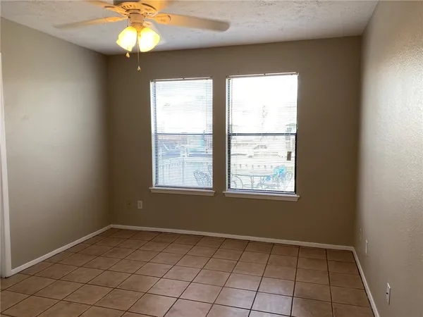an empty room with windows and way to kitchen