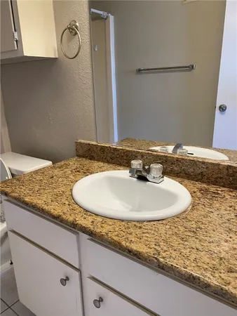 a bathroom with a granite countertop toilet sink and mirror