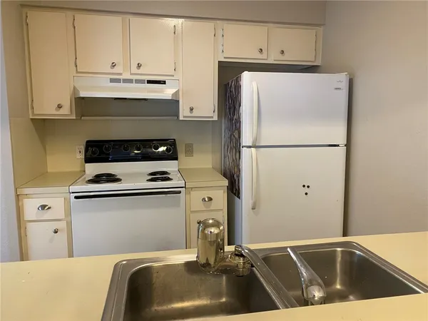 a kitchen with refrigerator a stove a sink and cabinets
